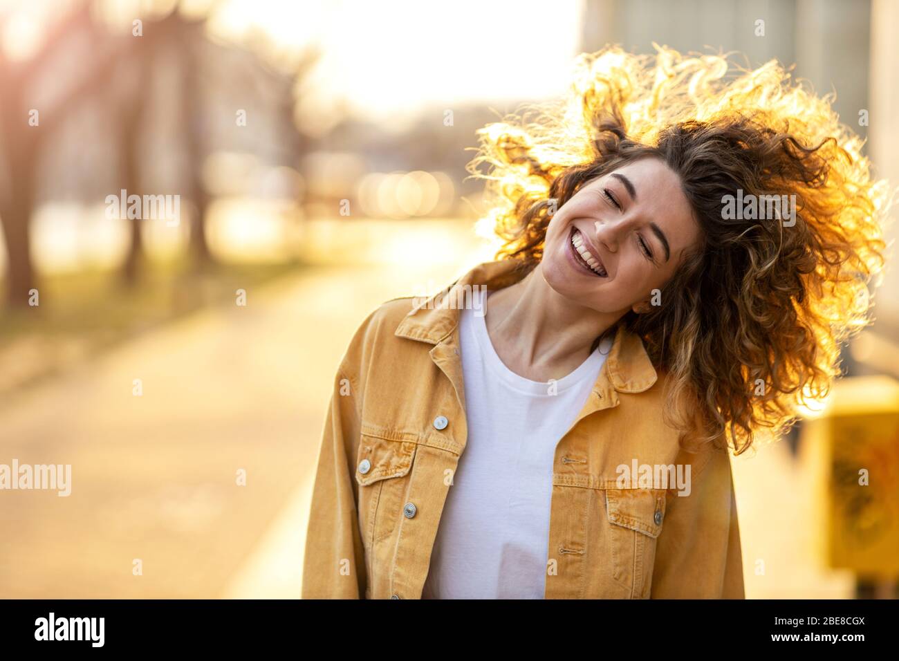Portrait of young woman with curly hair in the city Stock Photo - Alamy