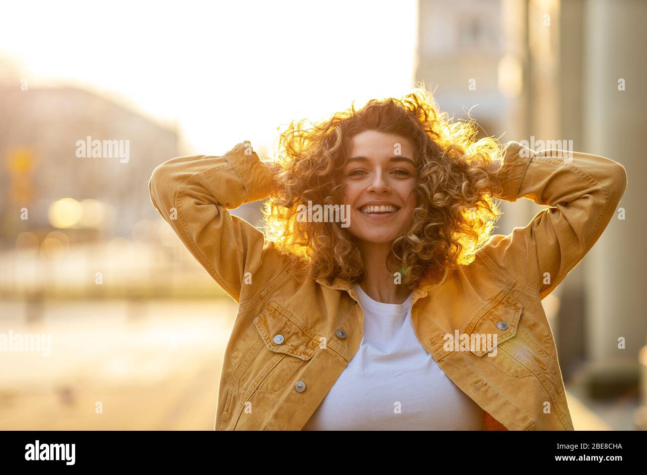 Portrait of young woman with curly hair in the city Stock Photo - Alamy