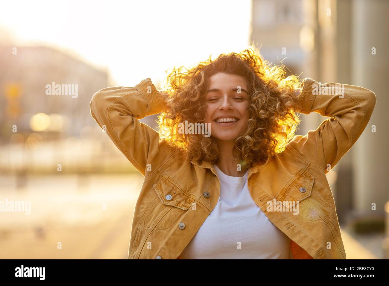 Portrait of young woman with curly hair in the city Stock Photo - Alamy