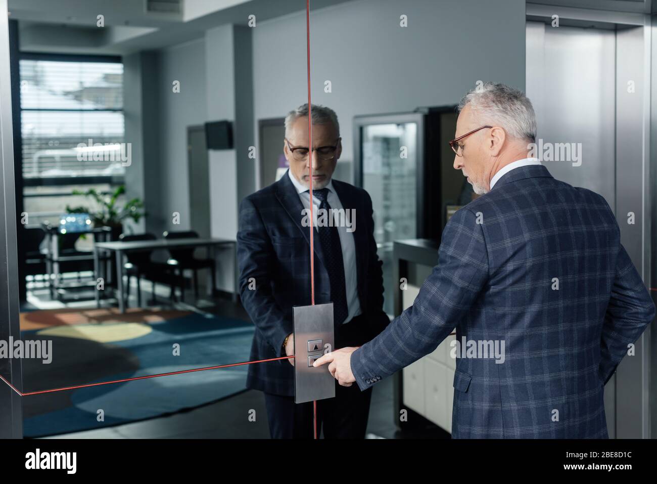 businessman in formal wear pushing button of elevator Stock Photo