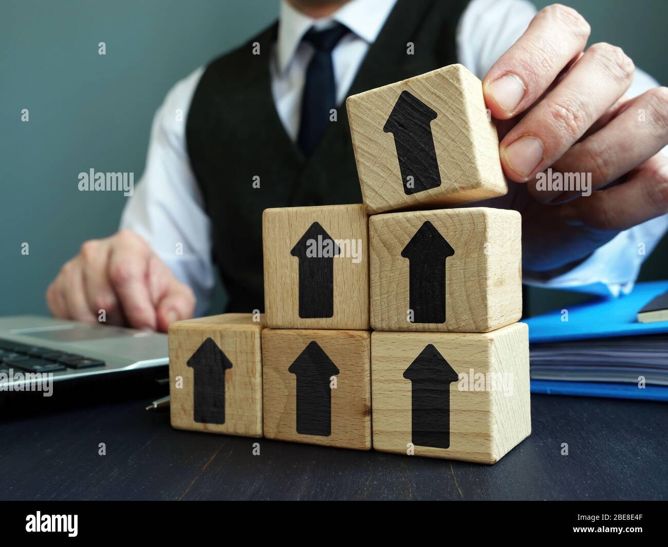 Growth business concept. Businessman makes ladder of success from blocks with arrows. Stock Photo