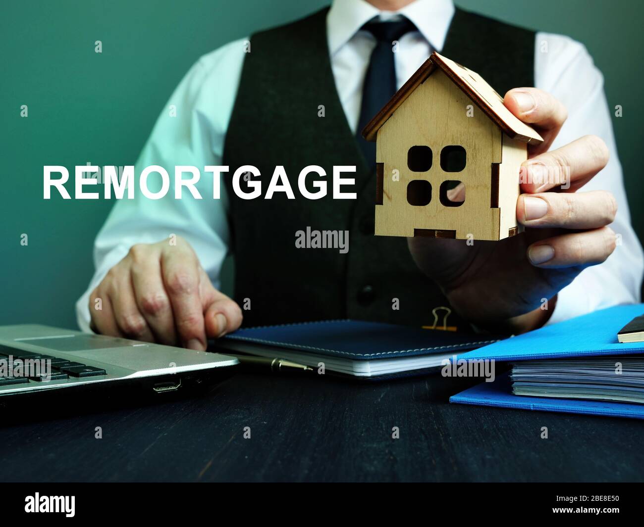 Man holds wooden home and sign remortgage. Stock Photo