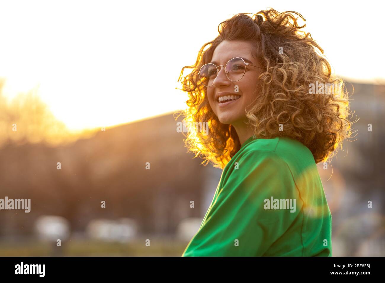 Portrait of young woman with curly hair in the city Stock Photo - Alamy