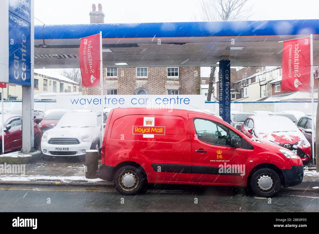A Royal Mail van parked in front of a used car dealership on Wavertree High Street in Urban Liverpool, England Stock Photo