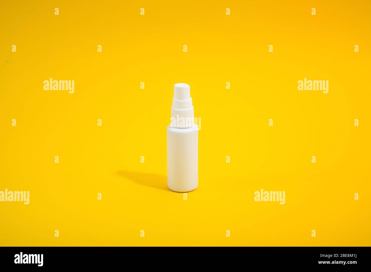 White smal plastic bottle with spray on yellow background with hard light. Mockup. Copy space. Medical antiseptic liquid for protection of virus Stock Photo