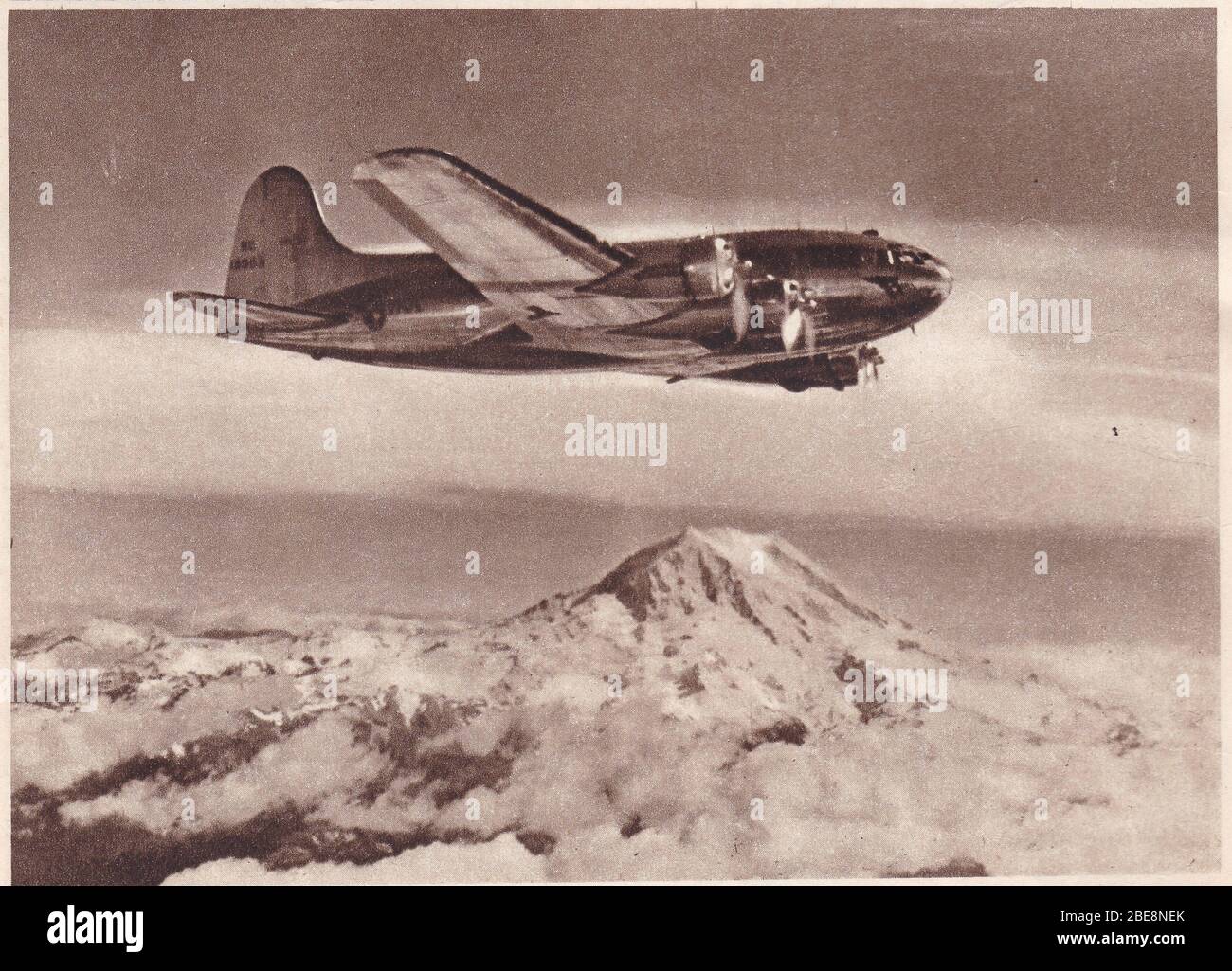 Vintage 1940s black and white photo of a Boeing strato-clipper belonging to Pan-America Airways flying over Puget Sound Mountains. Stock Photo
