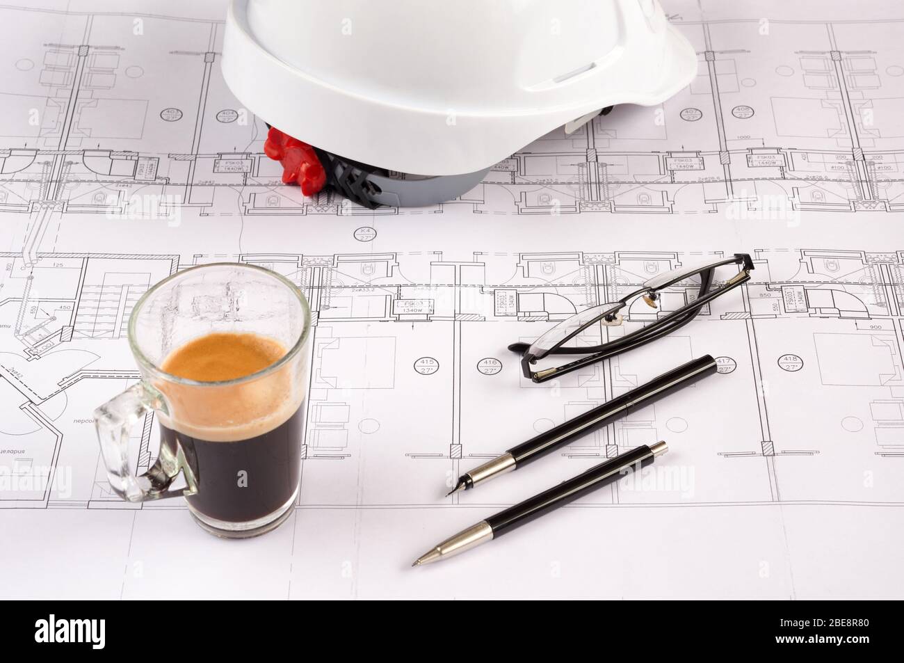 Architects workplace - architectural blueprints with safety helmet, glasses, propelling pencil and coffee on table. Top view. Stock Photo