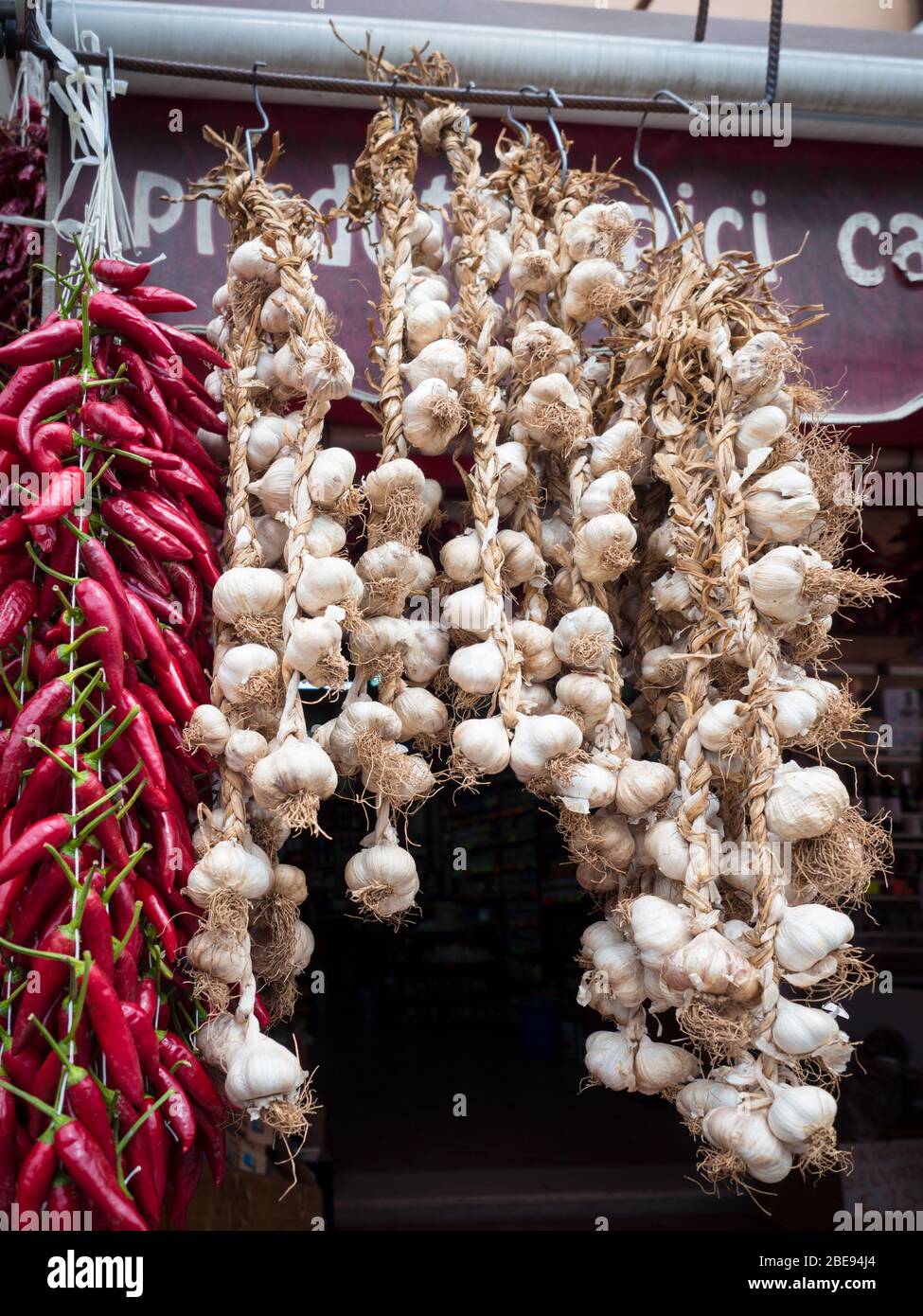 Calabrian chillies and garlic hung out to dry in the sun at a market. Stock Photo