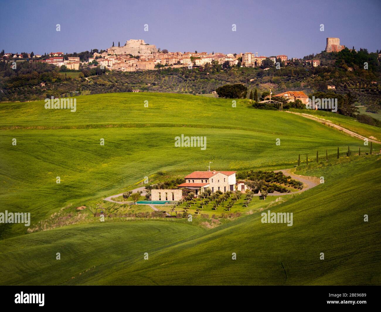 Hilly Tuscan landscape in spring. Green winding hills with scattered houses. Stock Photo
