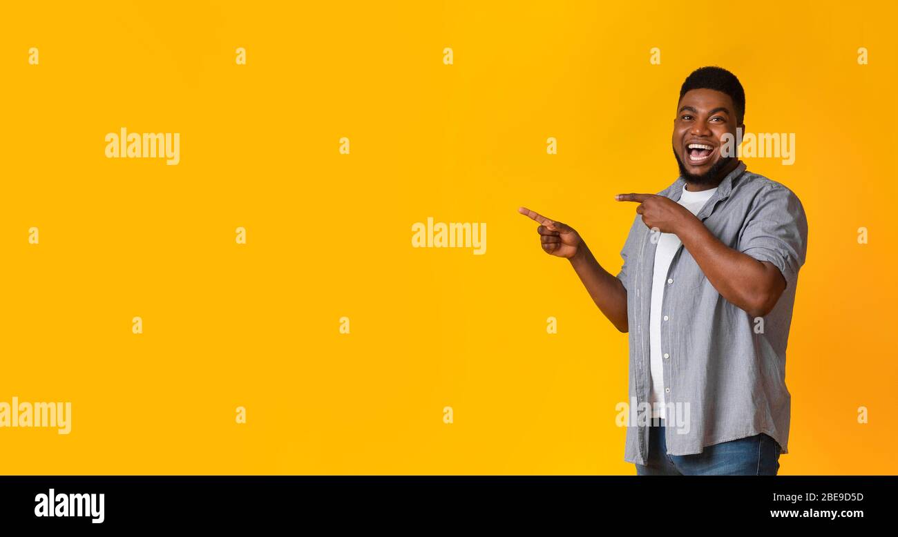 Great offer. Joyful black guy pointing aside at copy space Stock Photo