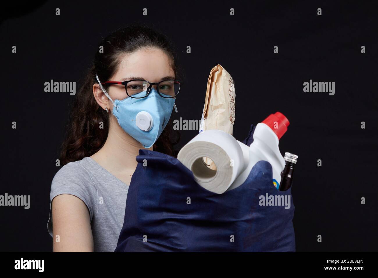 Young woman in a valve of the respiratory protective mask with a bag full of groceries from the supermarket. concept covidiots. Stock Photo