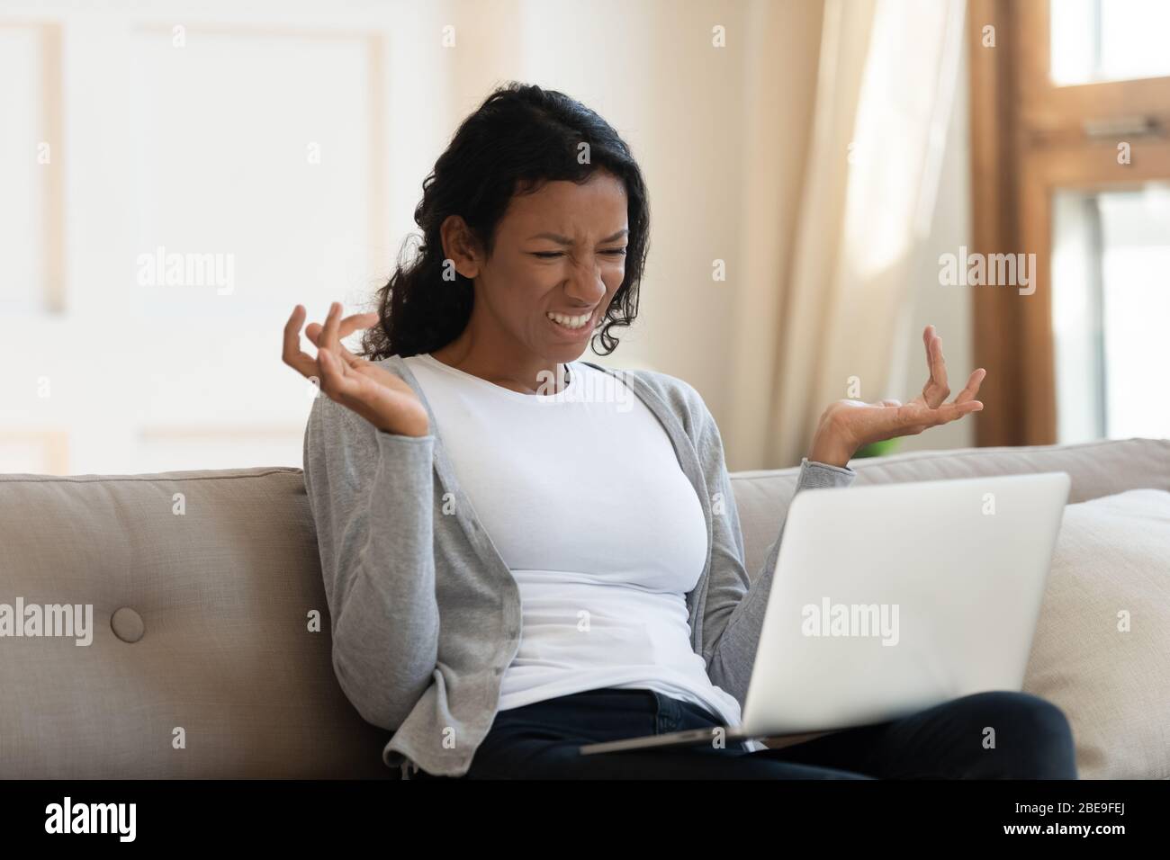 Annoyed young black girl looking at laptop screen Stock Photo