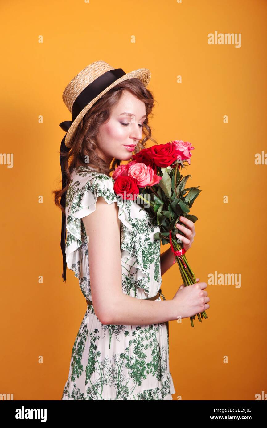 Portrait of attractive young woman in summer dress and straw hat ...