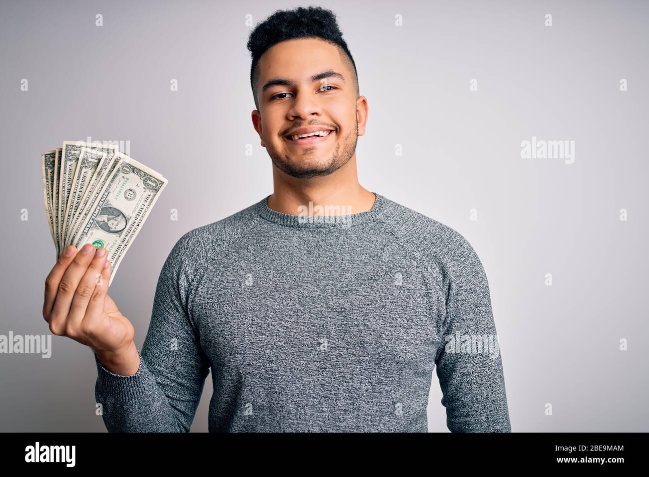 Young handsome man holding bunch of dollars banknotes over isolated ...