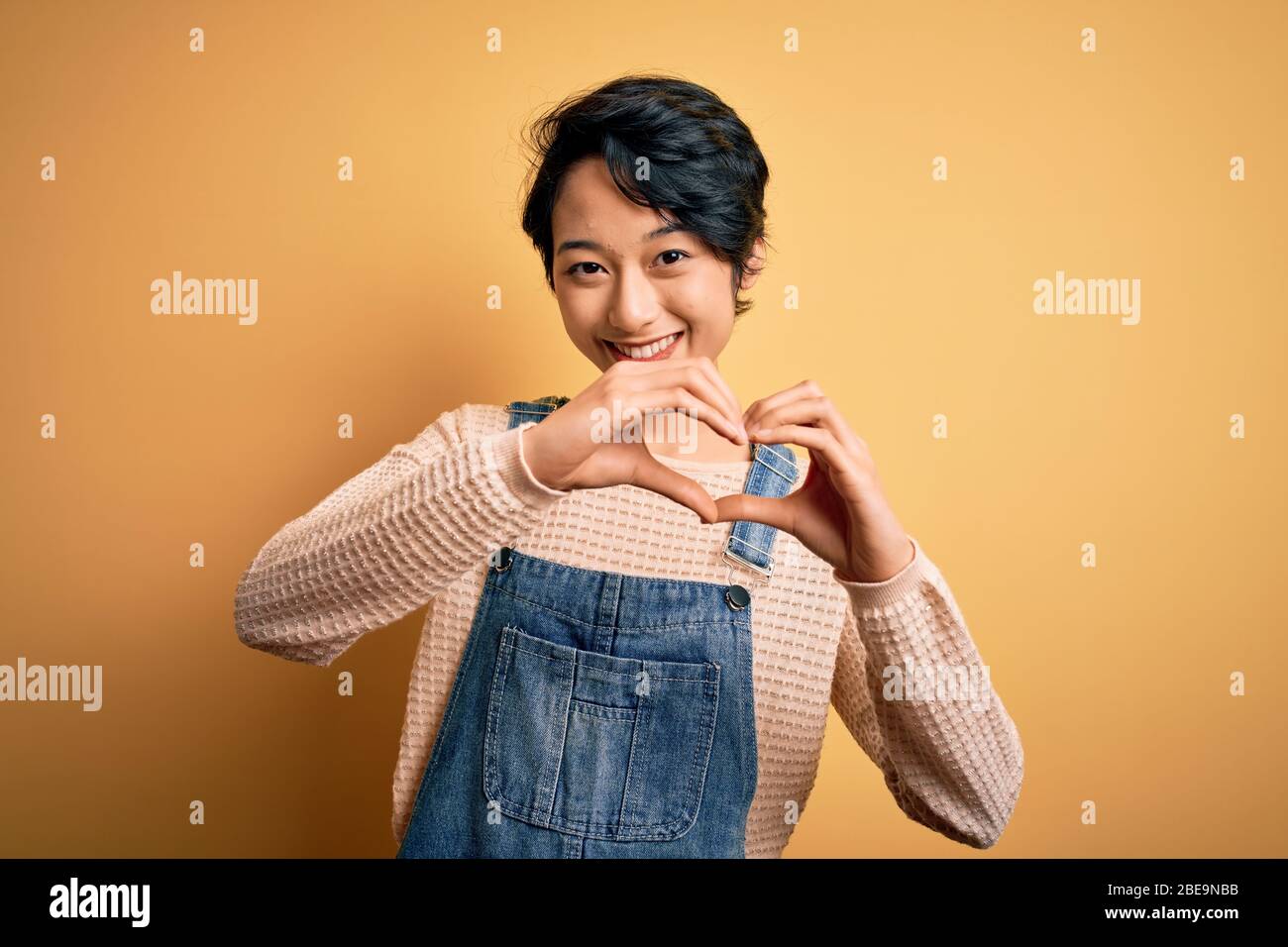 Young beautiful asian girl wearing casual denim overalls over isolated ...