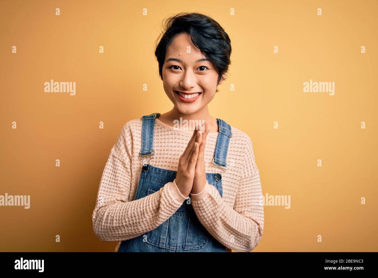 Young beautiful asian girl wearing casual denim overalls over isolated ...