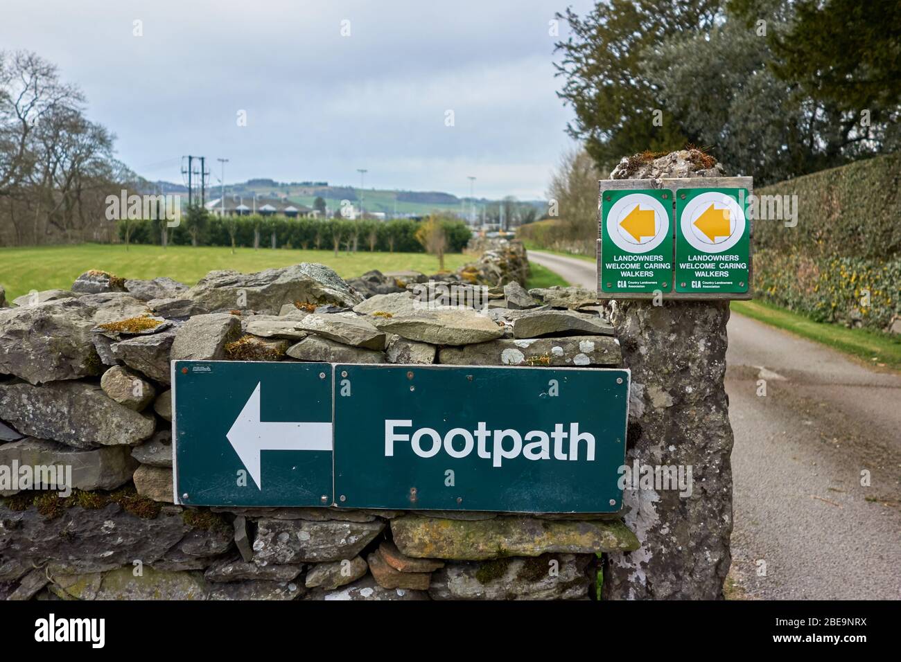 Green outdoor signs indicating the direction of a public right of way in the English countryside - Landowners Welcome Caring Walkers Stock Photo