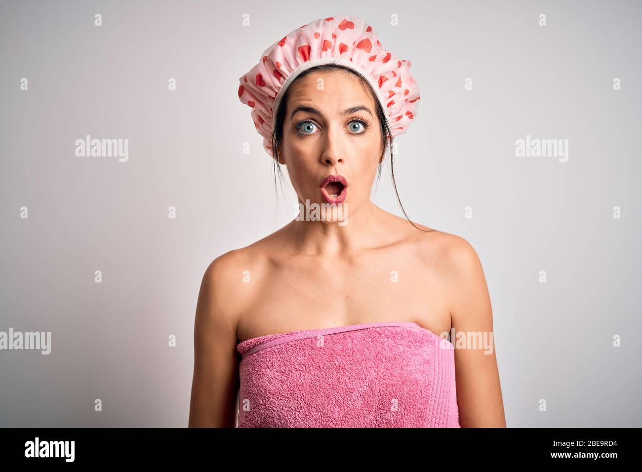 Young brunette woman with blue eyes wearing bath towel and shower cap ...
