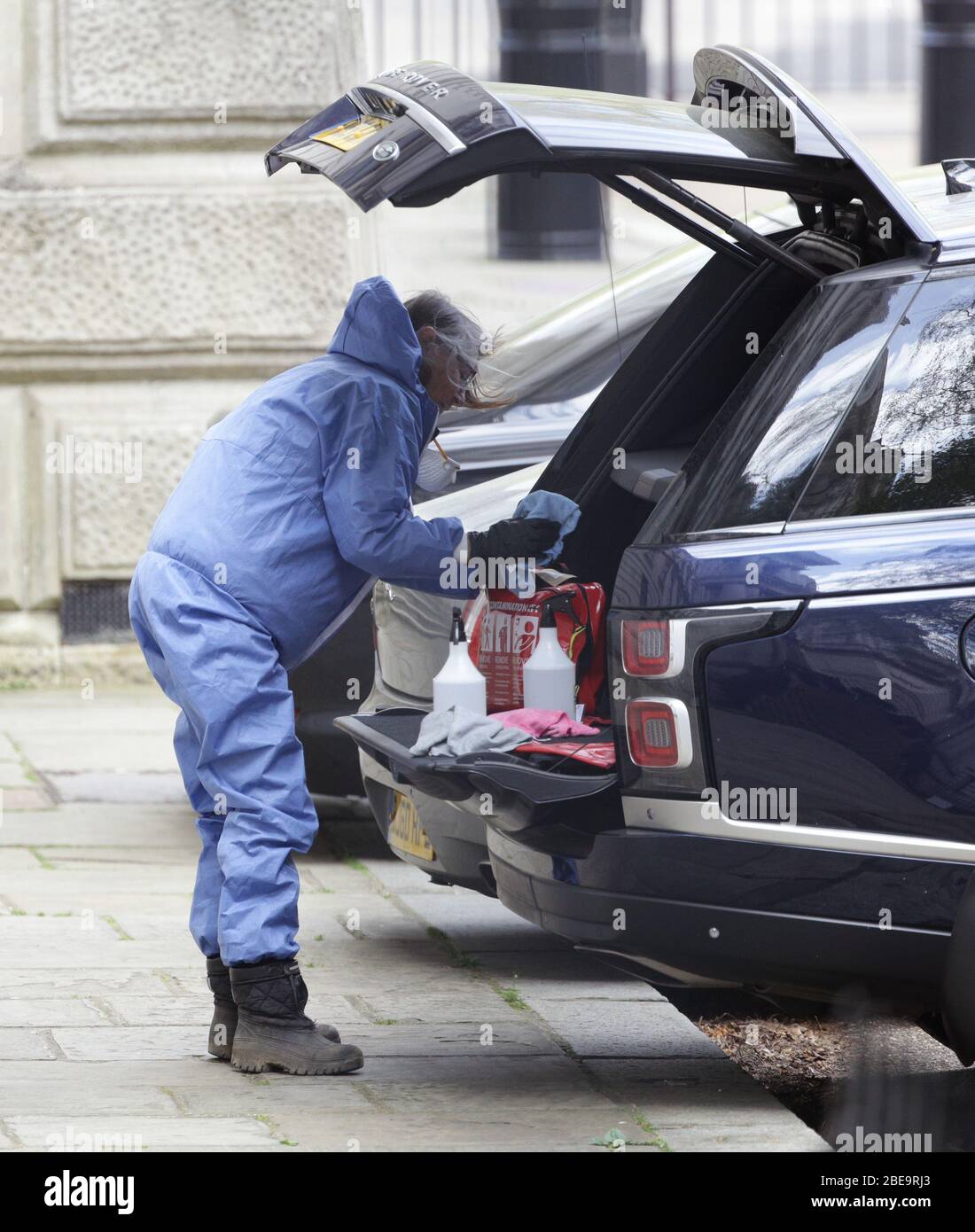 A woman wearing personal protective equipment (PPE) cleans an official car at the rear of No 10 Downing Street, London, after Prime Minister Boris Johnson was released from hospital where he had been undergoing treatment for coronavirus and headed to his country residence, Chequers in Buckinghamshire, to convalesce. Stock Photo