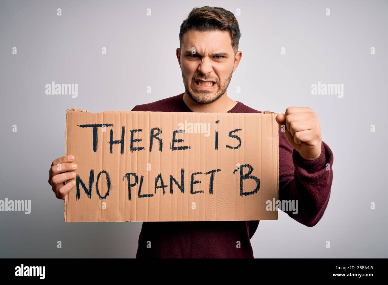 Young activist man holding protest banner for climate change and environment change annoyed and frustrated shouting with anger, crazy and yelling with Stock Photo