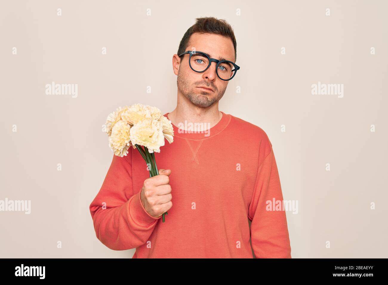Young handsome man with blue eyes holding bouquet of flowers over white ...