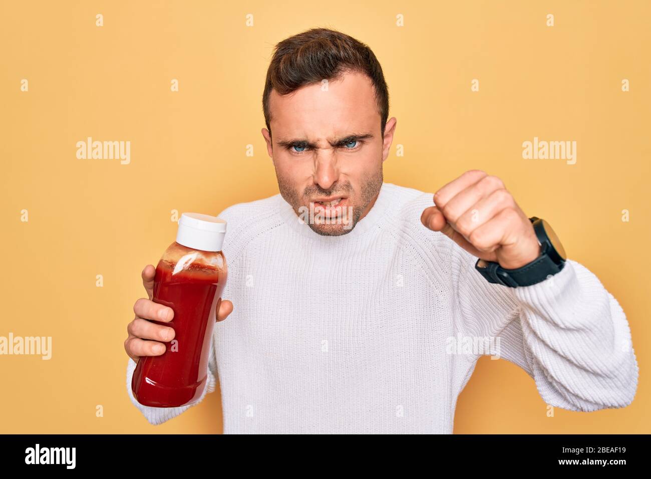 Young handsome man holding bottle of ketchup sauce condiment over yellow  background annoyed and frustrated shouting with anger, crazy and yelling  with Stock Photo - Alamy