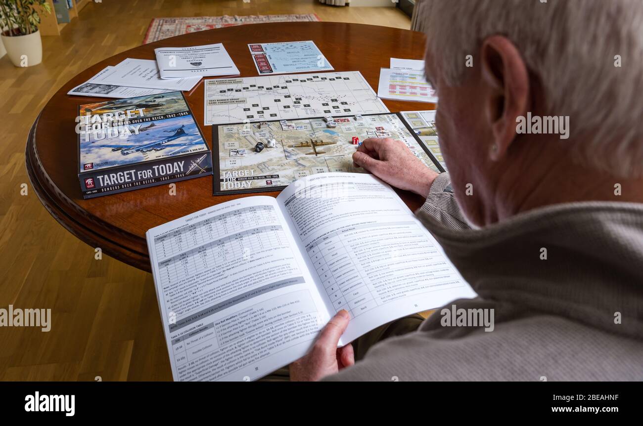 Senior man playing one player solitaire war board game called Target for Today set up on dining table in home, UK Stock Photo