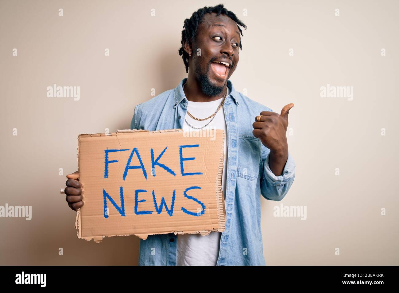 Young african american man holding banner with fake news message over ...