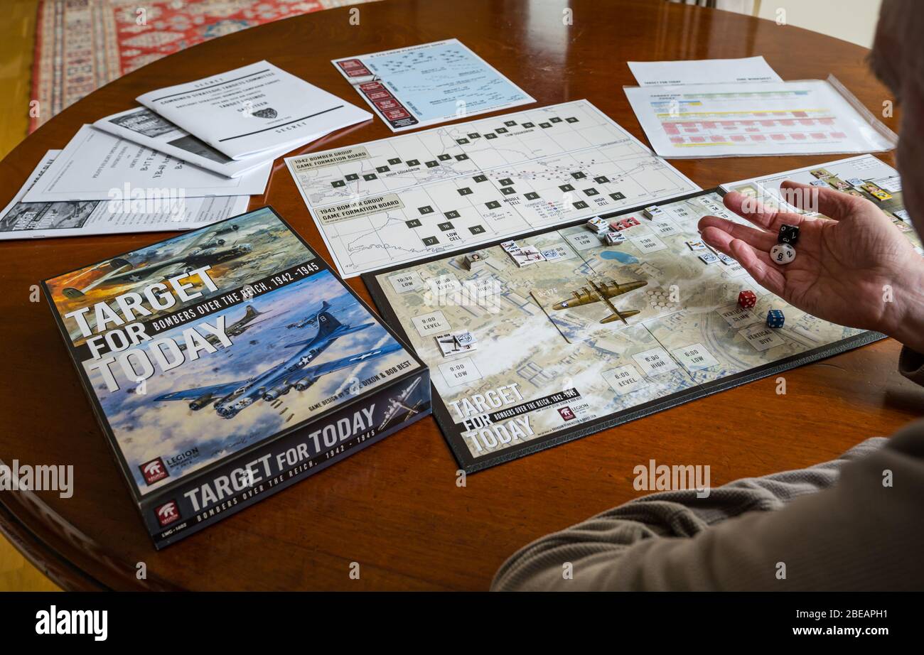 Senior man playing one player solitaire war board game called Target for Today set up on dining table in home, UK Stock Photo