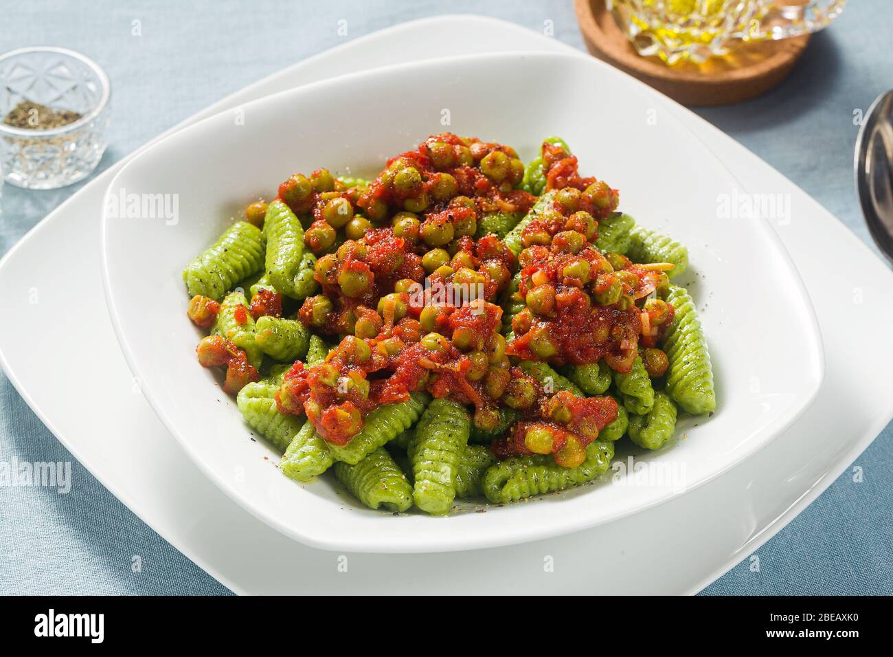 Italian fresh traditional sardinian pasta gnocchi with spinach and green pea tomato sauce. spring pasta for easter holidays. Stock Photo