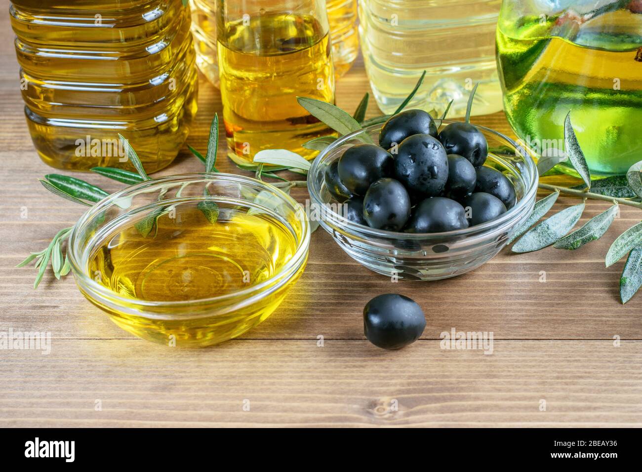 Black olives and olive oil in glass transparent bowls on the wooden ...