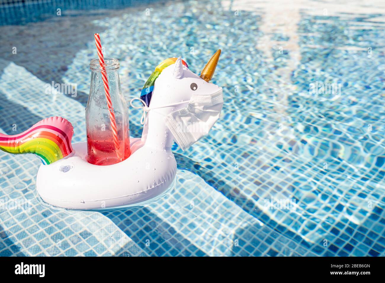 Swimming pool toy unicorn in a medical face mask. Concept of Coronavirus outbreak impact on a travel industry for summer season 2020 Stock Photo