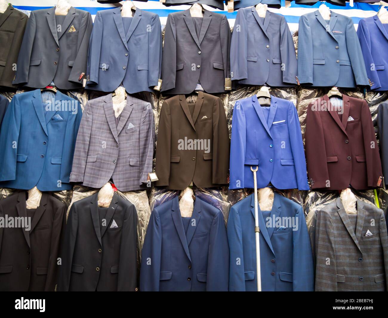 Rows of hanging new men's suits on the market. Stock Photo