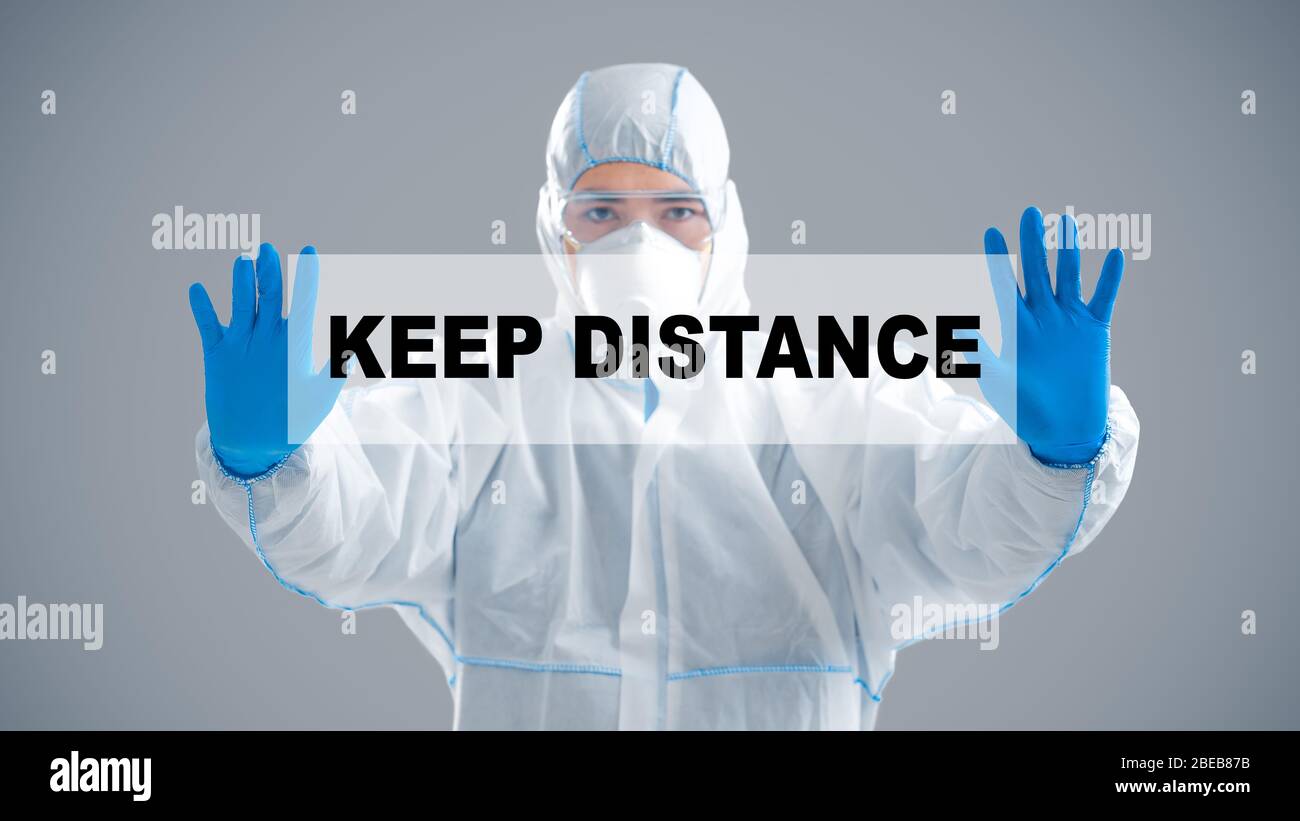 Asian man in protective suit holding inscription keep distance Stock Photo