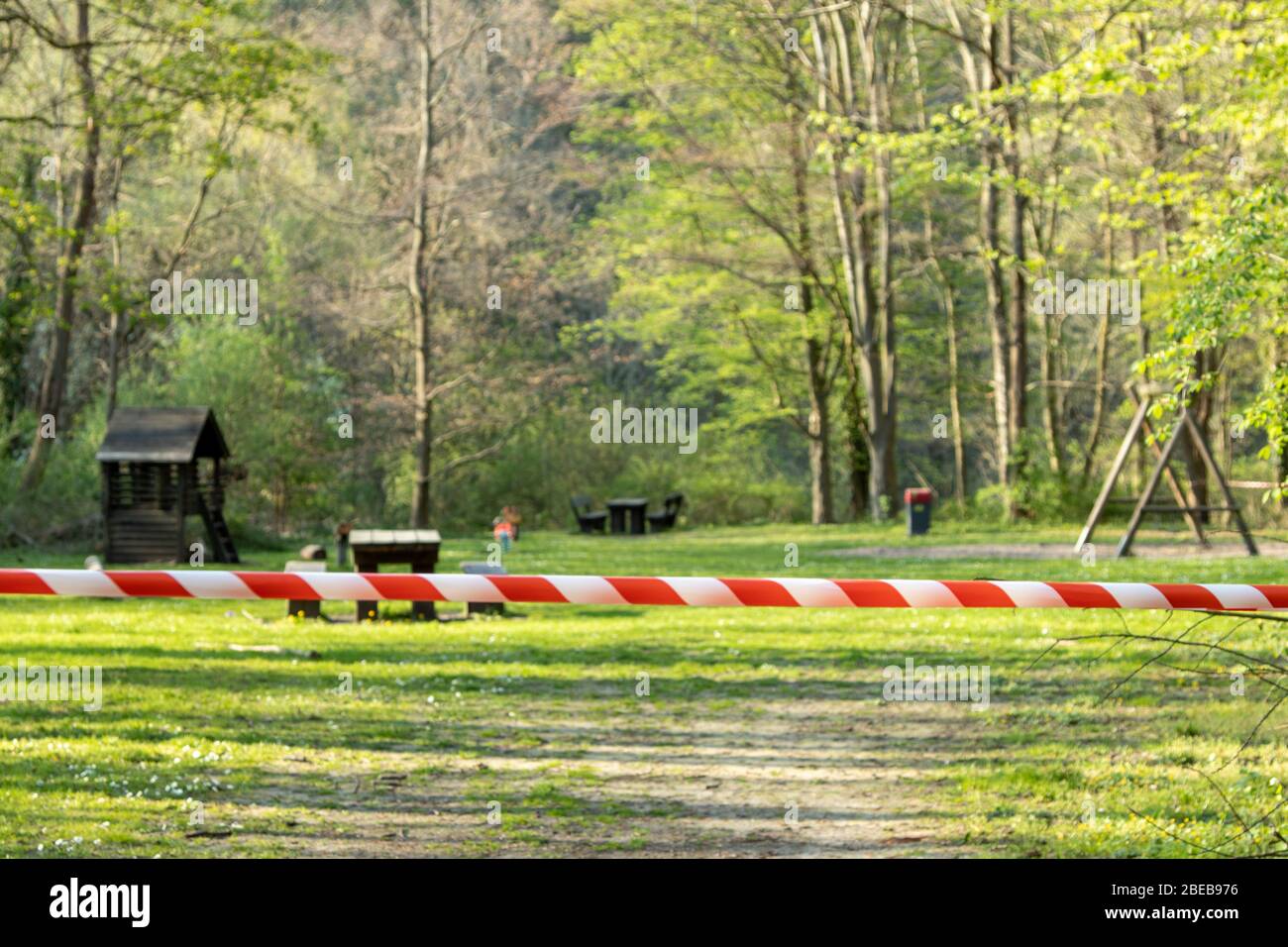 cordoned off playground, surroundet by trees, forcus on barrier tape Stock Photo