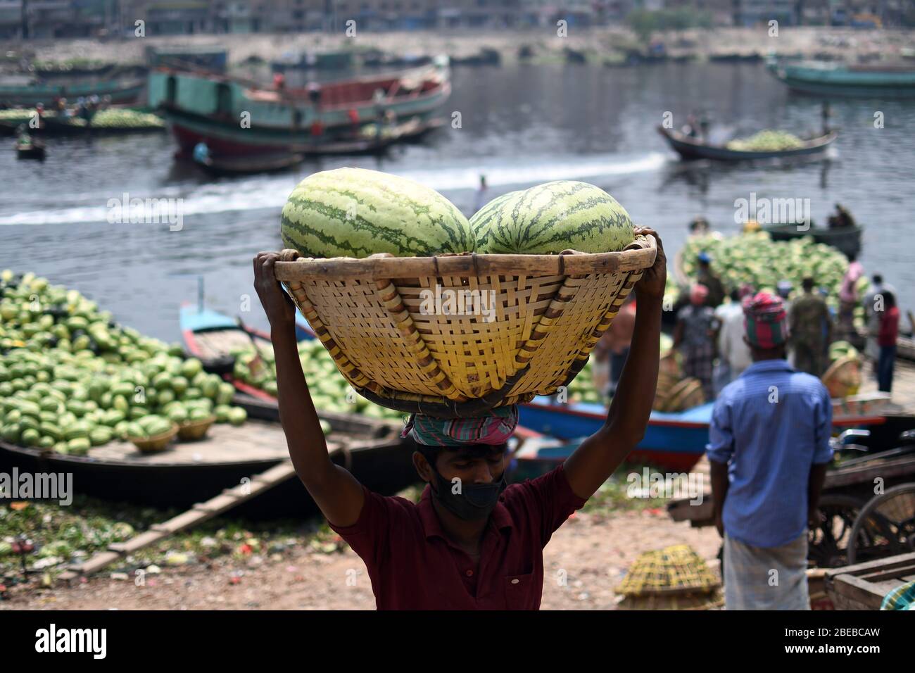 Bangladeshi labourers unload watermelons at a dock during a government-imposed lockdown as a preventive measure against the COVID-19 coronavirus in Dh Stock Photo