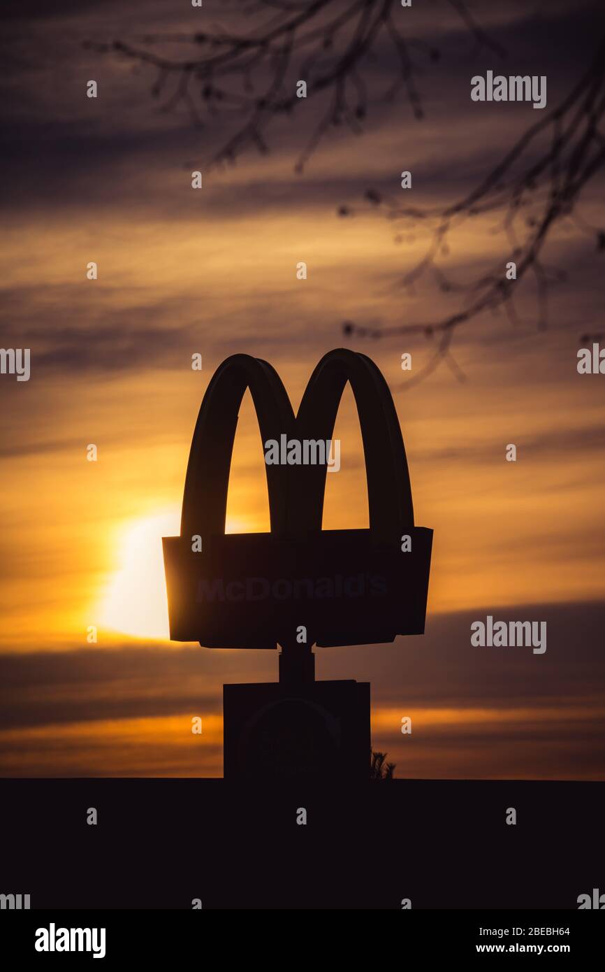 The famous Mcdonalds golden arches silhouetted against the sunrise sky Stock Photo