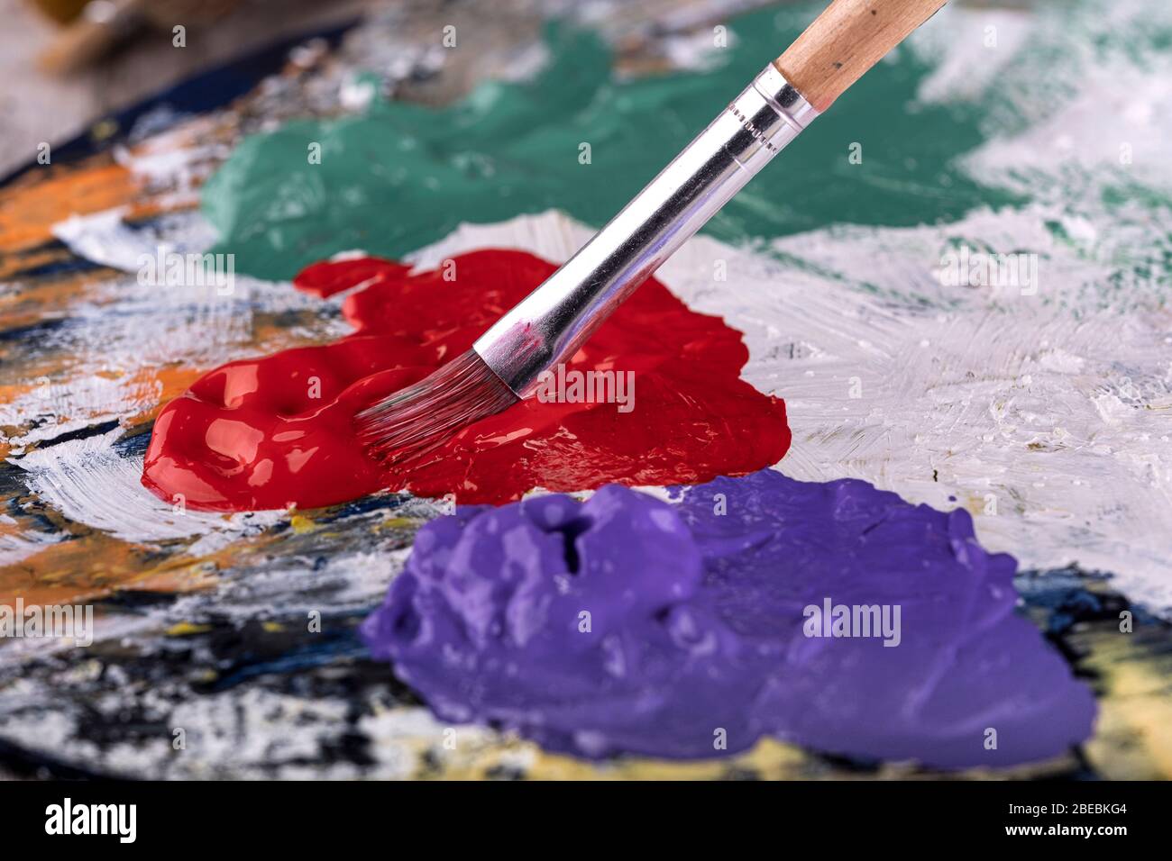 Fine art school. Closeup of artist hands holding wooden palette, mixing acrylic paint with brush. Stock Photo