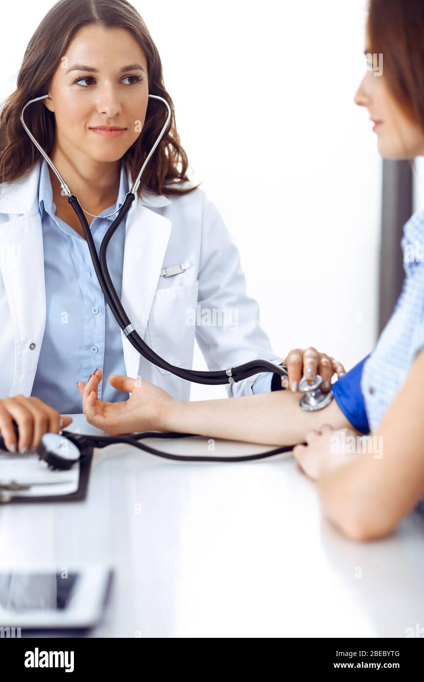 Doctor with a stethoscope in the hand examining her female patient ...