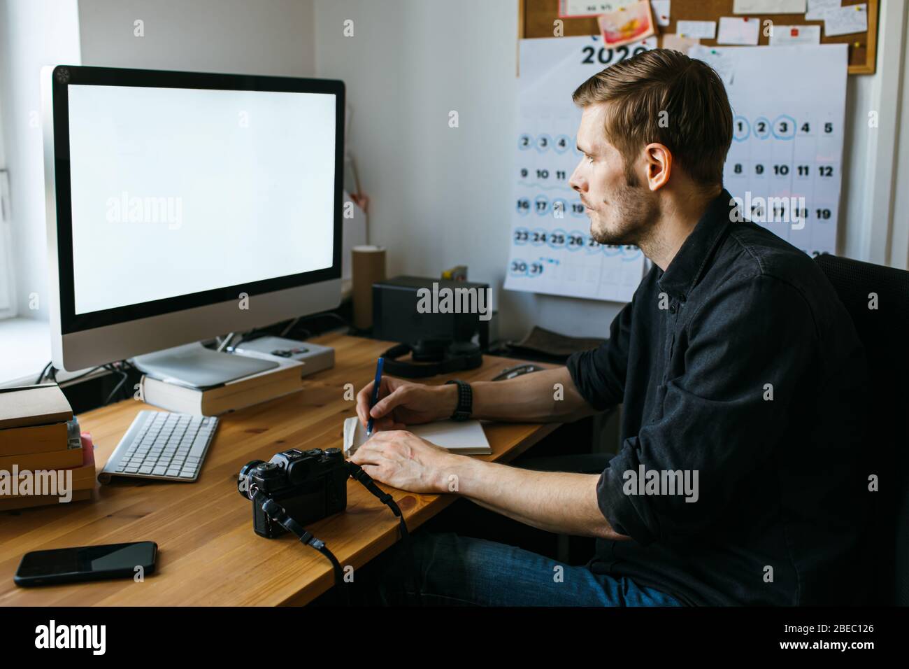 Man working from home office. Computer with blank empty screen for copy space and information. Businessman from behind shoulder view. Online classes Stock Photo