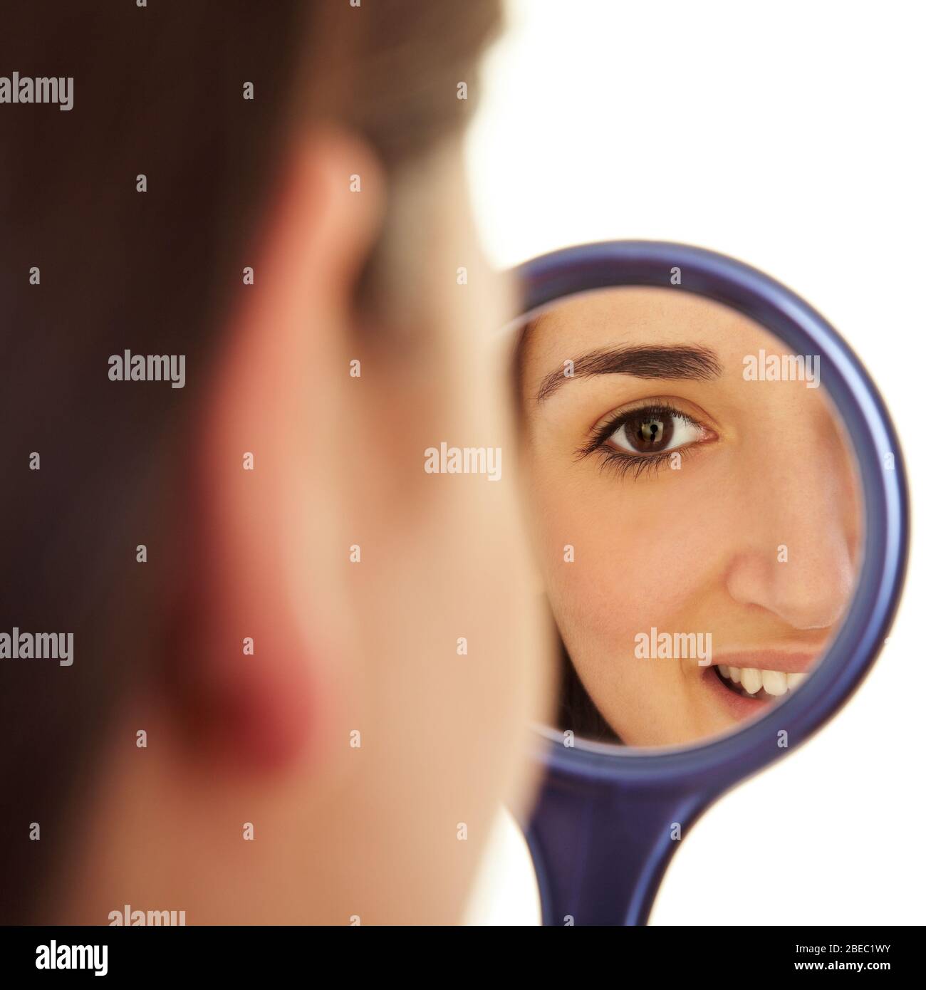 Young woman looks into a round hand mirror Stock Photo