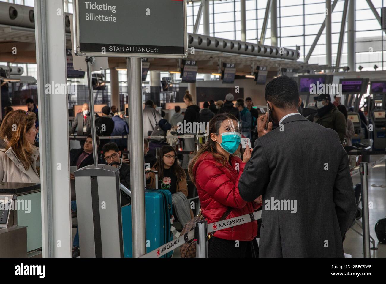 People wait to talk to representatives at the Air Canada ticket desk in Toronto's Pearson International airport, March 16, 2020. Amid security measures directed at slowing the spread of the COVID-19 virus, Canada's Prime Minister Justin Trudeau restricted travel to Canada, from many international countries. Pearson will be one of the designated airports in Canada that will be allowed to accept limited international flights. Stock Photo