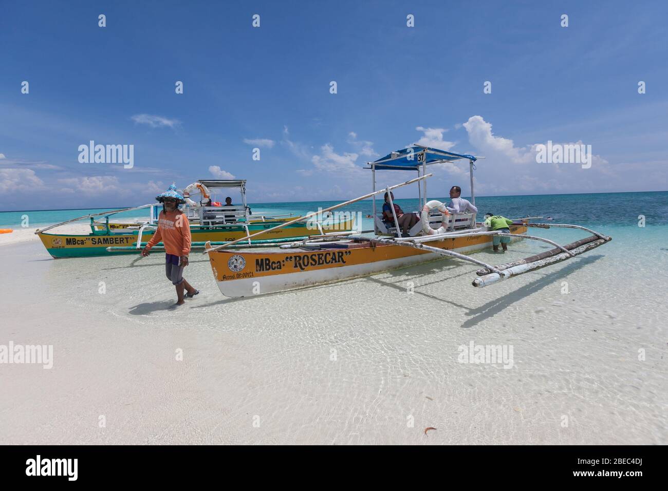 Camiguin Island, Camiguin, Philippines : local Philippine man and traditional outrigger boat with tourists on the white beach of sand Stock Photo