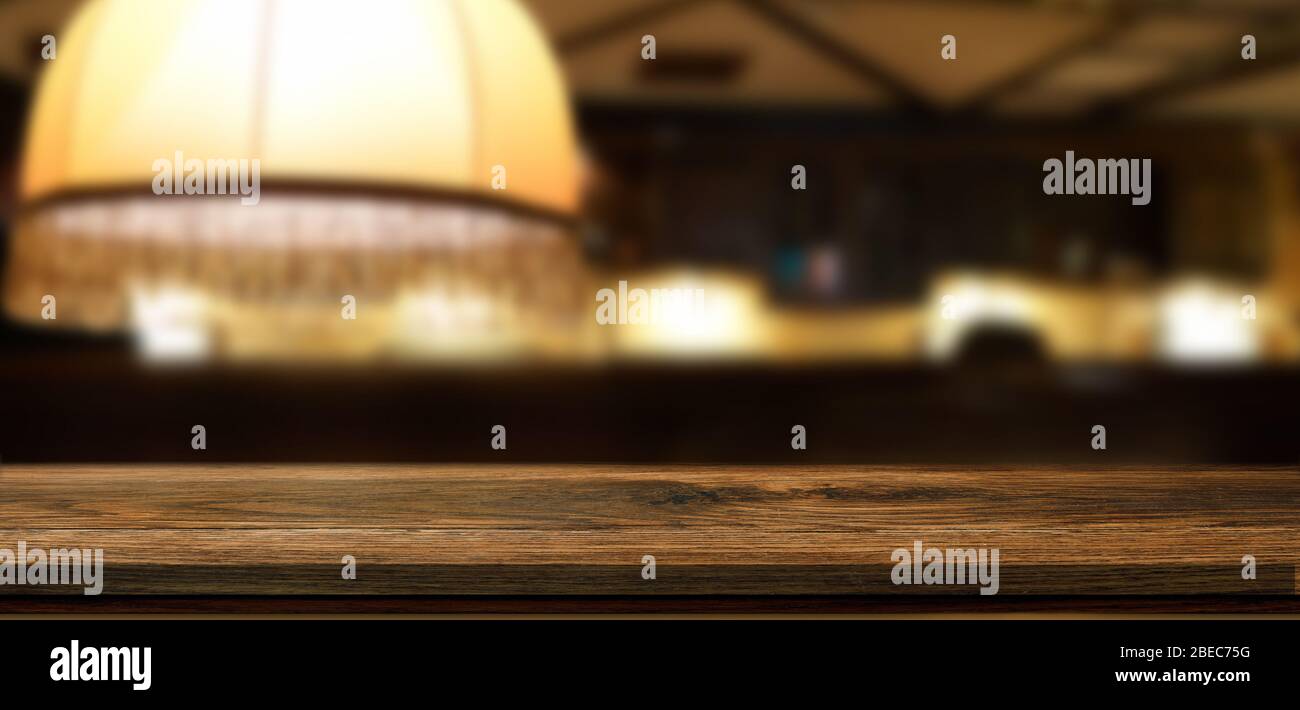 Empty wooden table in front of blurred bar background or restaurant background with light and bokeh for product montage display. Mockup for your Stock Photo