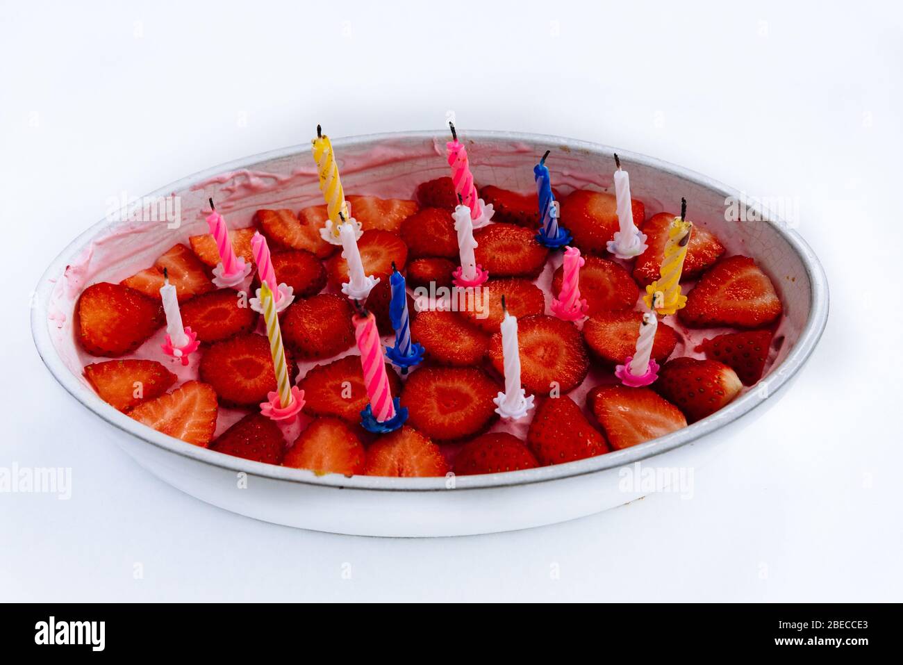 Homemade strawberry cake with birthday candles isolated on white