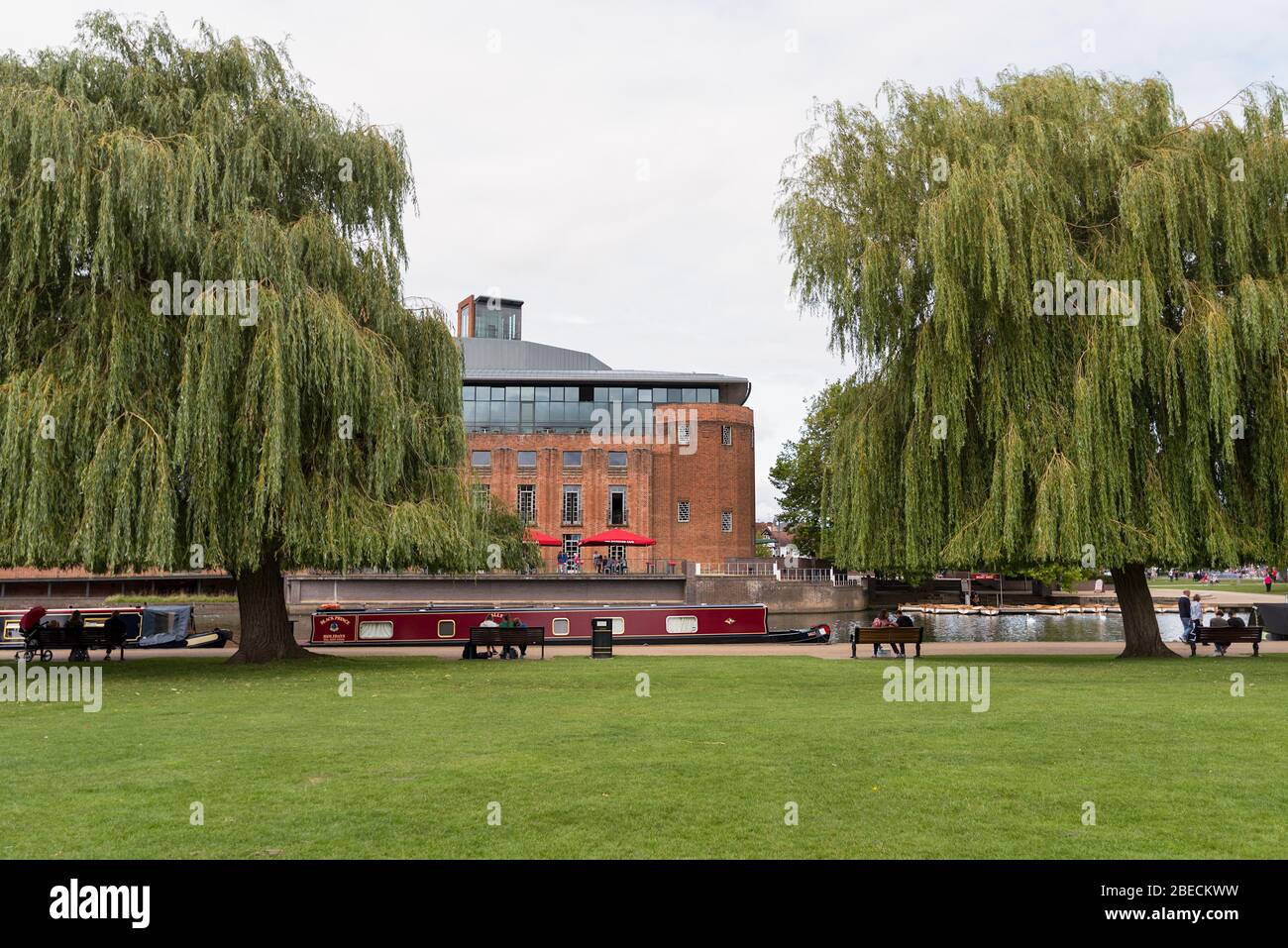 The landmark Royal Shakespeare theatre of Stratford on Avon viewed across the river Avon with canal boat and willow trees. Stock Photo