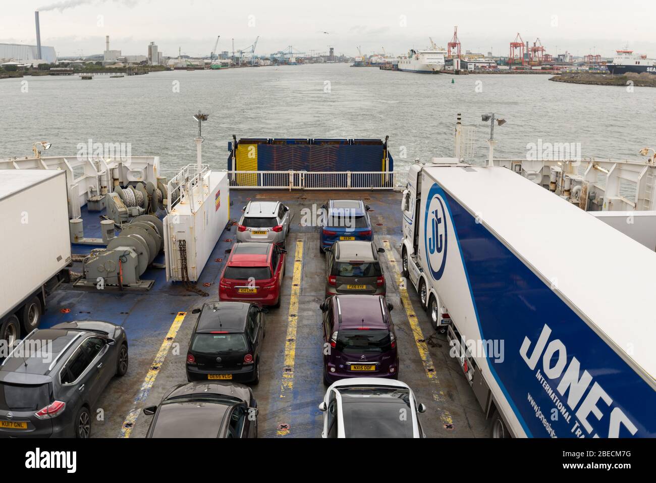 Departing Dublin port by commuter passenger ferry with the city and port in the background and cars and trucks on the deck. Stock Photo