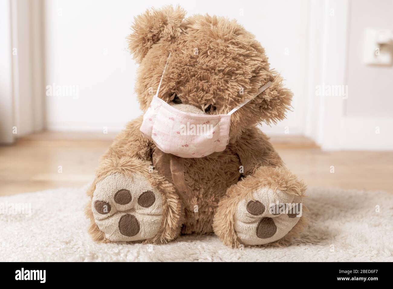 teddybear with a homemade covid 19 protection mask sitting on the floor Stock Photo