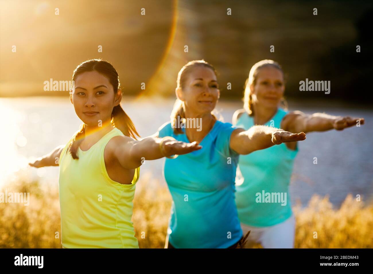 Three women practicing yoga next to a river Stock Photo