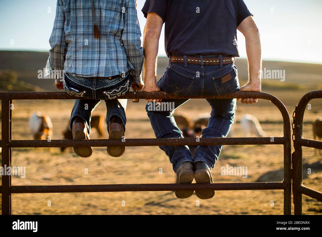 Mature couple sitting side by side on a fence on their ranch Stock Photo